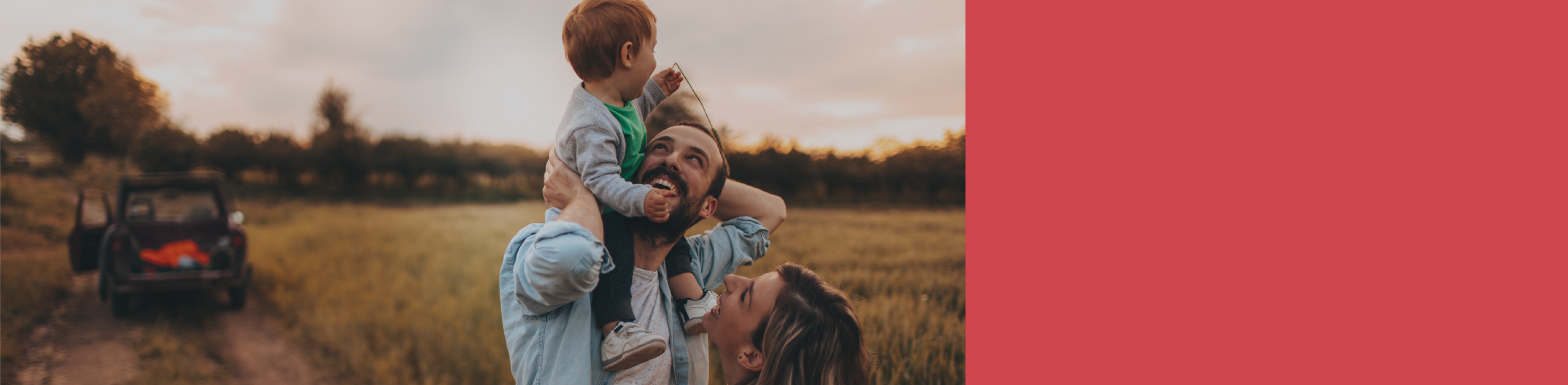 Fotografía de una familia feliz en el campo, donde el padre tiene a su hijo sobre los hombros. 